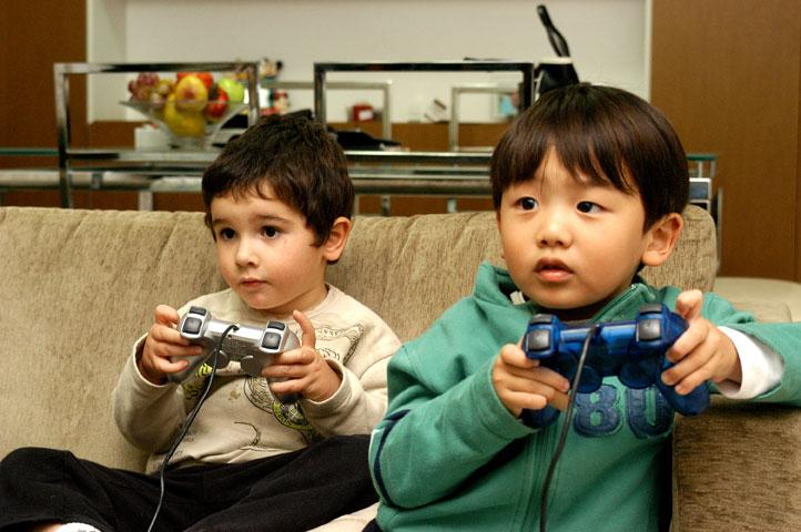 Menina olha como o menino joga o jogo online. dois meninos jogam