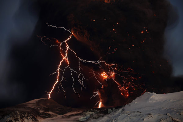 Lightning streaks across the sky as lava flows from a volcano in Eyjafjallajokul