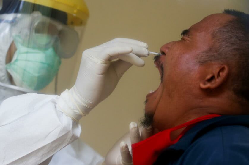 Técnica coletando amostra do nariz de homem para exame de coronavírus